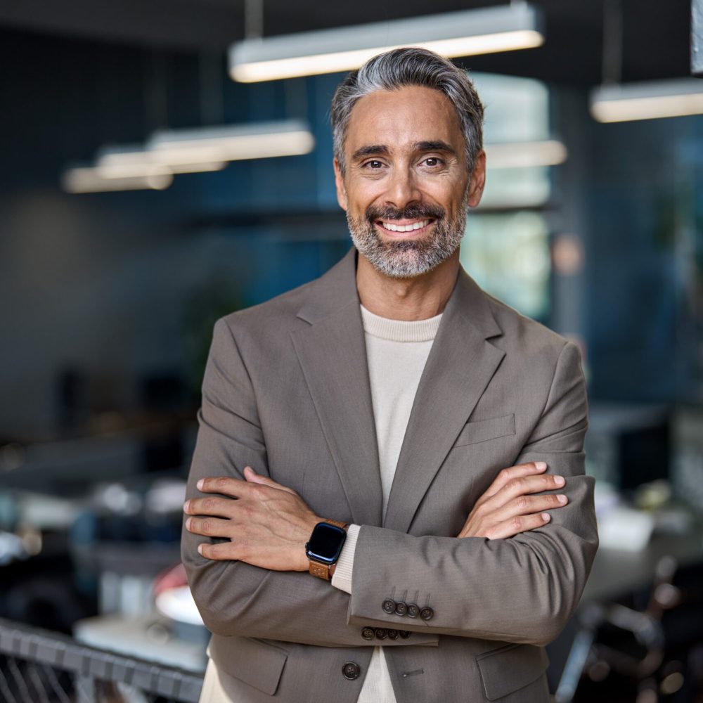Smiling middle aged ceo business man looking at camera, portrait. Confident happy mature older professional businessman executive manager, successful lawyer in suit standing arms crossed in office.